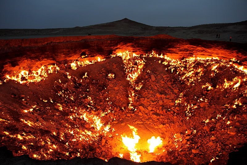 Terreno oscuro con una extensa zona rocosa iluminada por fuego.